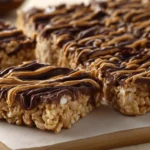 Peanut butter chocolate rice cake bars drizzled with chocolate and peanut butter on a cutting board.